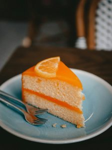 Close-up of a tempting orange cake slice served on a blue plate with a fork.