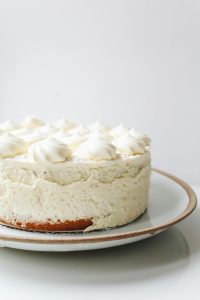 A mouth-watering vanilla cream cake with whipped topping on a ceramic plate.